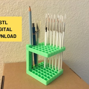 May include: A green plastic paintbrush holder with 48 slots. The holder is 3D printed and has the word "CUBISTAND" printed on the side. There are 18 paintbrushes in the holder.