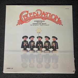 May include: A vinyl record album cover titled "Celebration" with the text "Christmas with the Haven of Rest" and the artist "The Quartet Truitt & Dean." The cover features five wooden figurines in black robes and hats, holding songbooks, with a star on a stick.