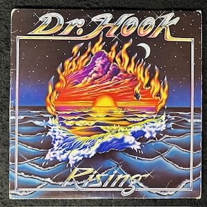 May include: A vintage vinyl record album cover featuring a psychedelic illustration of a fiery sunset over a blue ocean with the text "Dr. Hook Rising" in silver lettering.