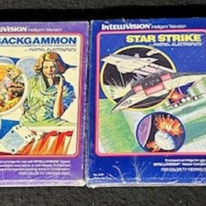 May include: Four Intellivision video game cartridges, each with a different game title. The cartridges are wrapped in plastic and have colorful artwork. The games are: Mr. Basic Meets Bits 'N Bytes, Backgammon, Star Strike, and Night Stalker.