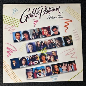 Può includere: Una copertina di un album in vinile bianco con un design colorato. Il titolo dell'album è "Gold & Platinum Volume Four" e presenta un collage di ritratti di celebrità.