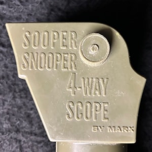 Puede incluir: Un juguete periscopio de plástico verde con las palabras "Sooper Snooper 4-Way Scope By Marx" impresas en él.