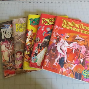 May include: A collection of five vintage Ringling Bros. and Barnum & Bailey Circus programs featuring colorful illustrations of tigers, clowns, and circus performers. The covers display bold typography and vibrant red, yellow, and white graphics.