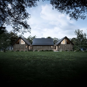 The back of the cabin features expansive natural wood siding and a sloping asymmetrical roofline, seamlessly blending with the surroundings. Large asymmetrical windows in the loft area at each end of the home offer striking views and natural light