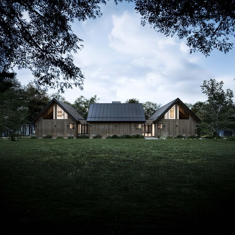 The back of the cabin features expansive natural wood siding and a sloping asymmetrical roofline, seamlessly blending with the surroundings. Large asymmetrical windows in the loft area at each end of the home offer striking views and natural light