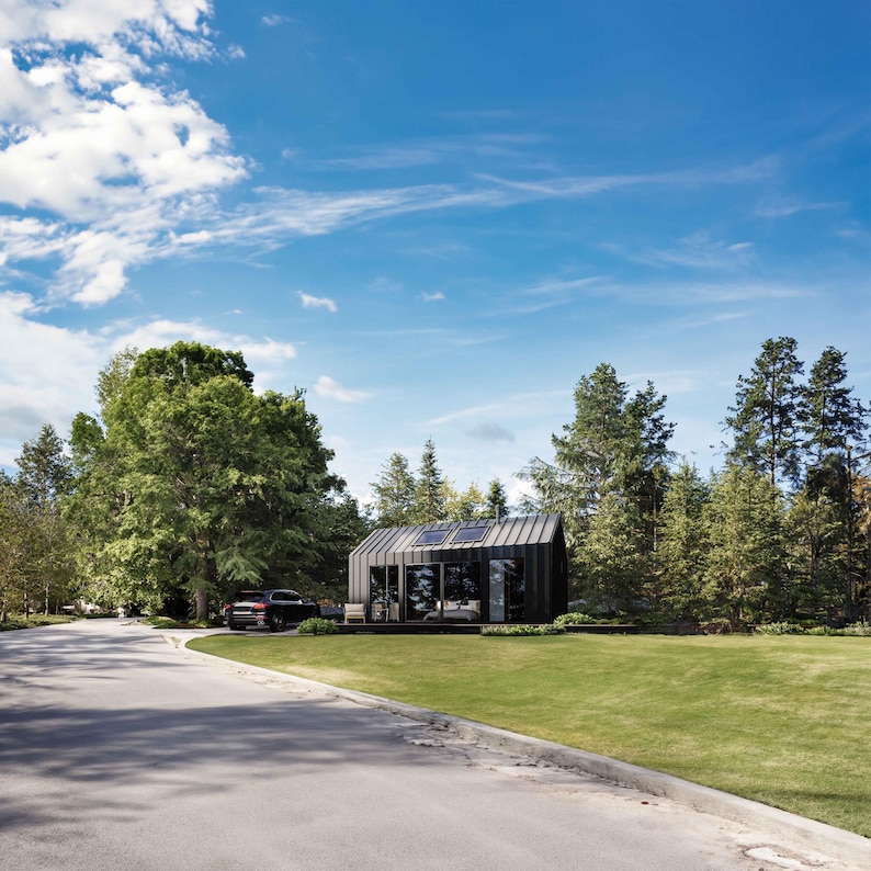 Cabin view showcasing vast sliding glass doors and oversized windows, inviting abundant natural light into the interior. The open layout blurs indoor-outdoor boundaries, fostering a tranquil connection with nature. A contemporary cabin aesthetics