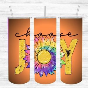May include: Three orange tumblers with lids and straws. The tumblers have the words "Choose Joy" written on them in black script. The "J" and "Y" are decorated with gold glitter. A colourful tie-dye sunflower is in the centre of the tumblers.