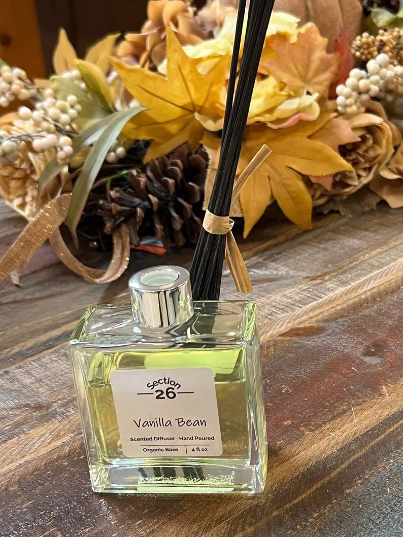 Puede incluir: Una botella de vidrio transparente con una tapa plateada y una etiqueta que dice "section -26- Vanilla Bean Difusor arom&aacute;tico - Hecho a mano Base org&aacute;nica | 4 fl oz".