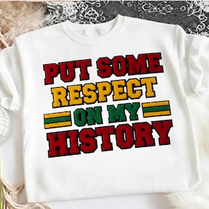 May include: White sweatshirt with the text "PUT SOME RESPECT ON MY HISTORY" in red, yellow, and green lettering. The sweatshirt has a crew neck and short sleeves. The text is in a bold, collegiate-style font.