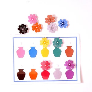 Puede incluir: Un juego de emparejamiento con recortes de flores y jarrones de colores. El juego incluye flores y jarrones rosas, azules, amarillos, verdes, naranjas, marrones, rojos, morados y grises.