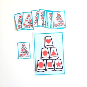 May include: A set of printable cards for a shape matching game. The cards feature a variety of shapes, including hearts, stars, squares, and pentagons. The cards are designed to be used with cups, and the shapes are printed on the bottom of the cups. The game is designed to help children learn about shapes and colors.