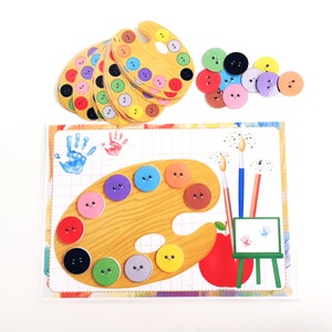 May include: A colorful wooden paint palette with smiling faces on each paint well. The palette is surrounded by colorful circles with smiling faces, and there are two handprints on the left side of the image.