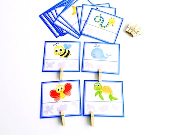 May include: A set of blue cards with images of a bee, whale, butterfly, and turtle. Each card has a matching shadow underneath. The cards are designed for a matching game and come with wooden clothespins.
