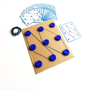 May include: A handmade educational game featuring a cardboard base with blue bottle caps and rubber bands. Includes a set of blue-bordered cards with dot patterns. A green rubber band is also included.