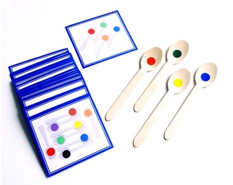 Puede incluir: Un juego de cucharas de madera con puntos de colores en la parte superior. Las cucharas están dispuestas en fila sobre una superficie blanca. También hay varias tarjetas azules con bordes blancos y puntos de colores en ellas.