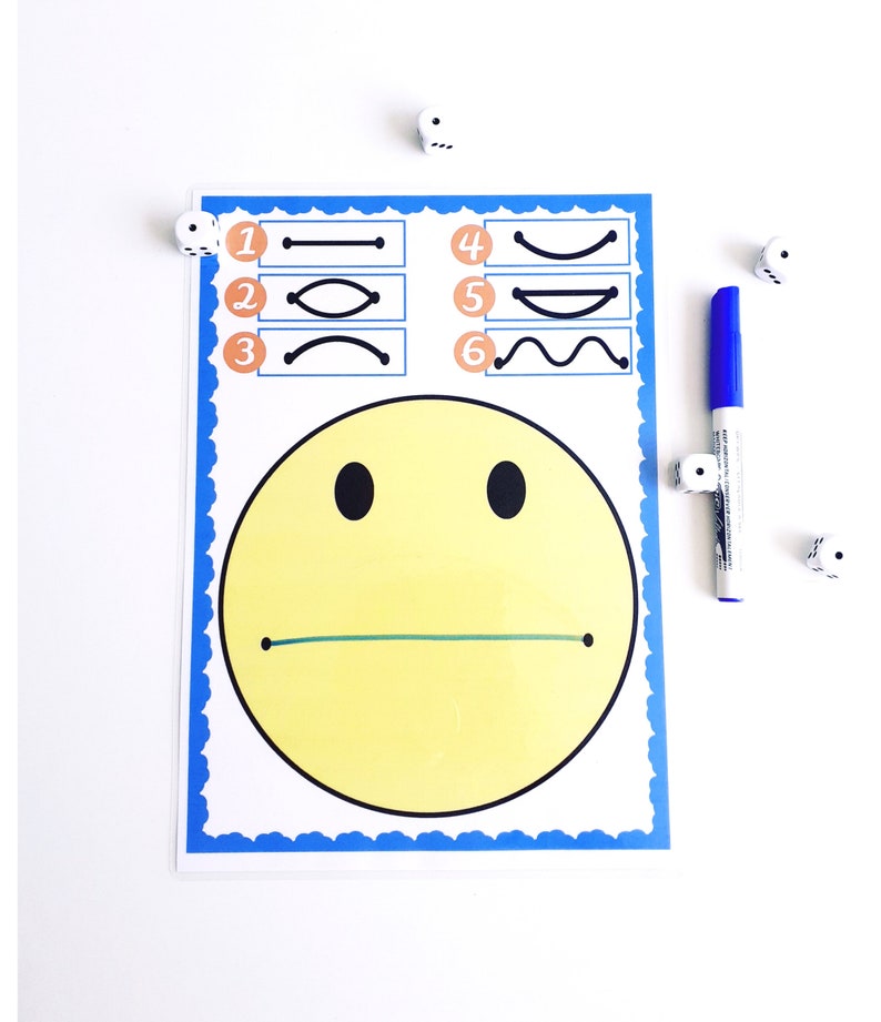 May include: A yellow smiley face chart with black eyes and a green line for a mouth. The chart has a blue border and includes numbered line variations. A blue marker and dice are also present.
