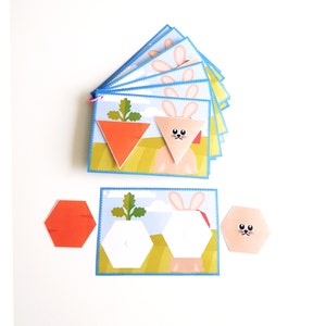 Op de afbeelding: Een set kleurrijke viltpuzzelstukken in de vorm van een wortel en een konijn. De stukken zijn ontworpen om kinderen vormen en kleuren te leren.