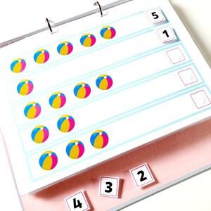 May include: A colorful learning activity with a binder and pages featuring beach ball images and number cards. The numbers 1, 2, 3, 4, and 5 are visible.