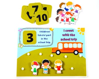 May include: A colorful felt board with a bus, children, and numbers. The text on the board reads "child(ren) take(s) part in the school trip. I count with the school trip."