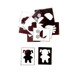 May include: A set of black and white silhouette cards featuring various shapes, including a stroller, a cloud, a hand, a flower, and a car. There are also two cards with a silhouette of a girl, one black and one white.