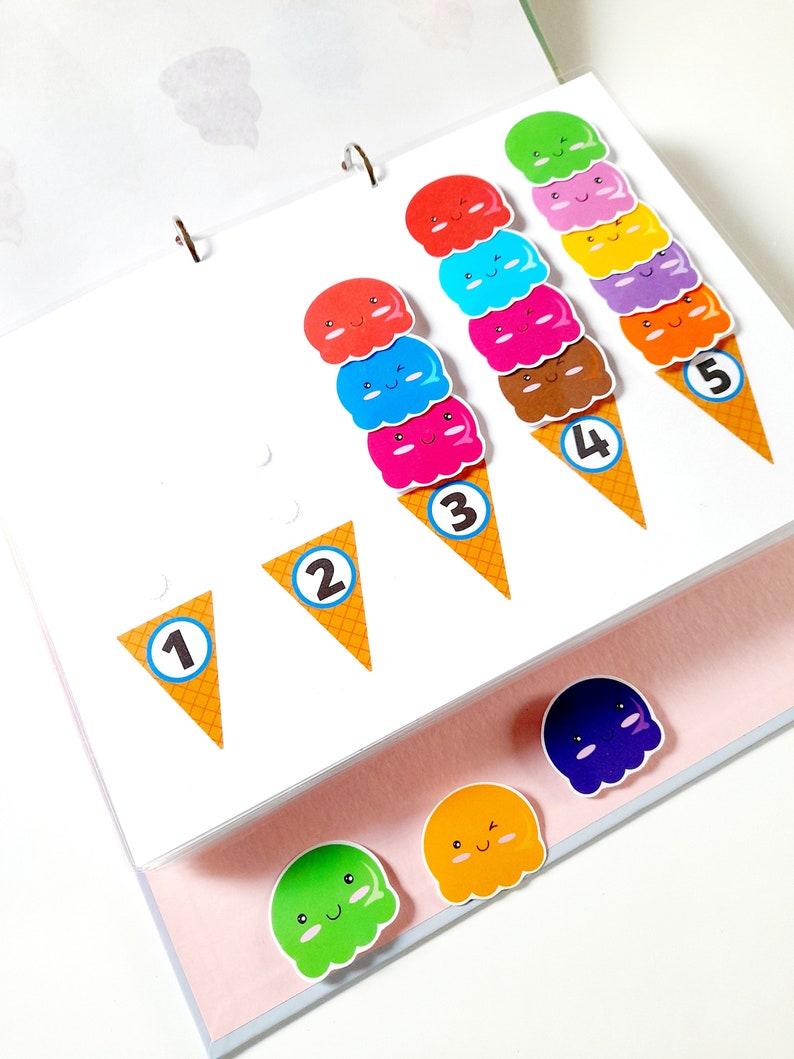 May include: A colorful ice cream cone counting activity with numbers 1 through 5.  The ice cream cones are decorated with smiling faces and are arranged in order of quantity.  There are also three loose ice cream cones in different colors.