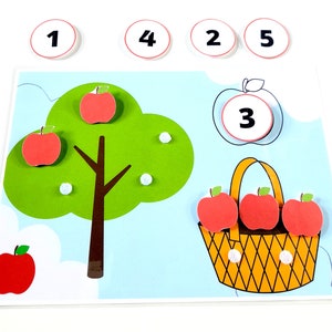 Puede incluir: Un juego educativo colorido para niños con un árbol verde con manzanas rojas, una cesta con tres manzanas rojas y círculos numerados con los números 1, 2, 3, 4 y 5.