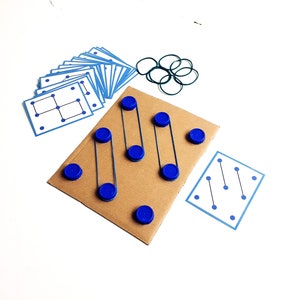 May include: A handmade educational game featuring a cardboard base with blue bottle caps and rubber bands. Includes blue cards with dot patterns and a set of green rubber bands. The game is designed for learning and development.