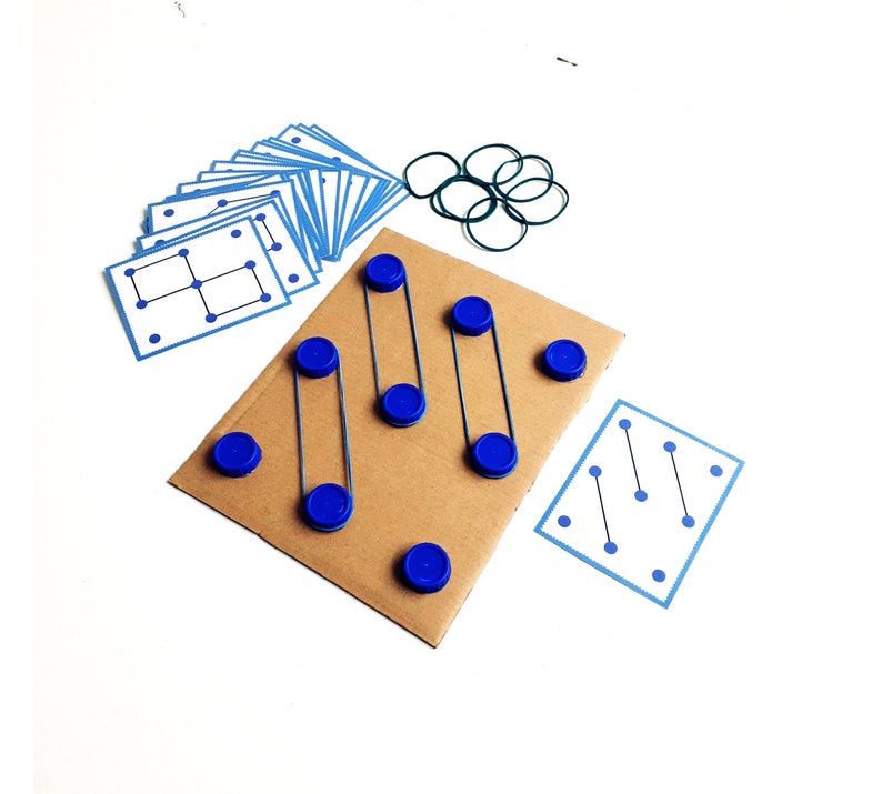 May include: A handmade educational game featuring a cardboard base with blue bottle caps and rubber bands. Includes blue cards with dot patterns and a set of green rubber bands. The game is designed for learning and development.