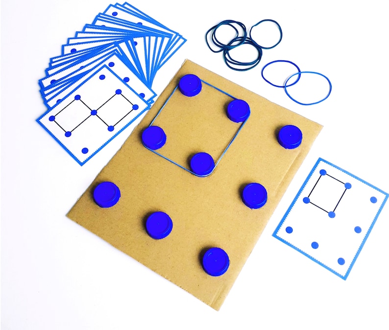 May include: A collection of educational game components, including a cardboard base, blue bottle caps, blue rubber bands, and printed cards with dot patterns. The game is designed for learning and problem-solving, with a focus on visual and spatial reasoning.