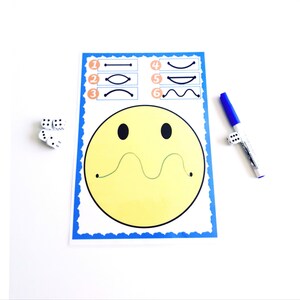 May include: A yellow smiley face activity sheet with a blue border, featuring line tracing exercises. Includes a blue marker and dice for interactive play. The sheet has a wavy line for tracing and numbered examples.