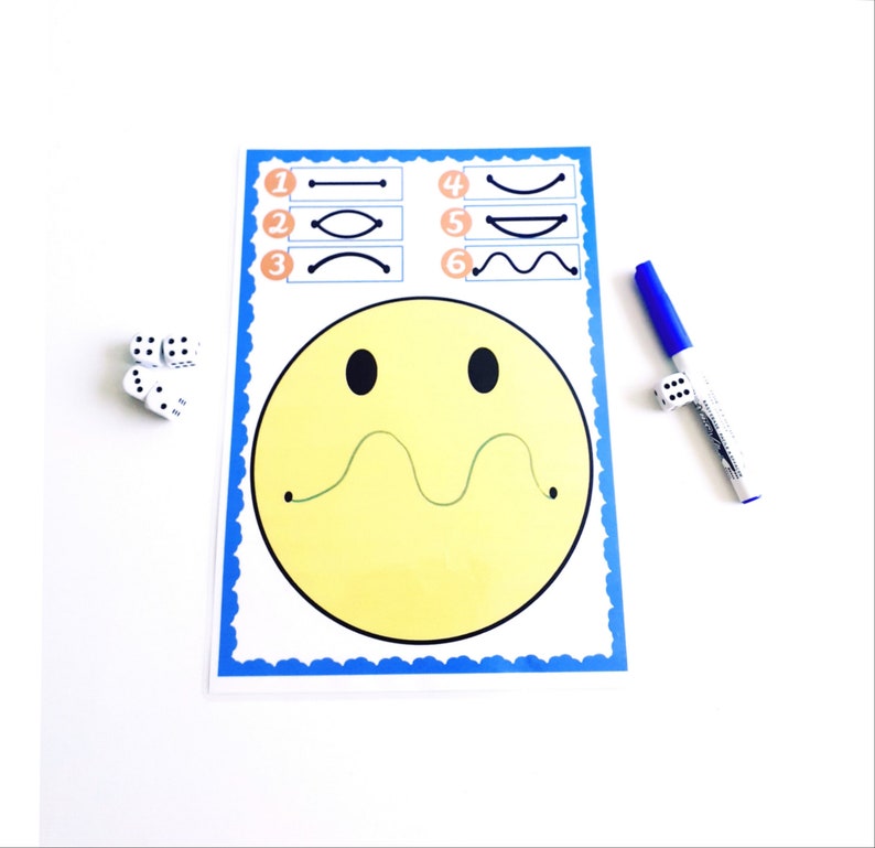 May include: A yellow smiley face activity sheet with a blue border, featuring line tracing exercises. Includes a blue marker and dice for interactive play. The sheet has a wavy line for tracing and numbered examples.