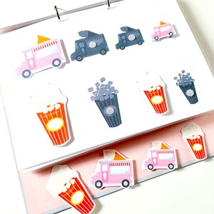 May include: A set of colorful stickers featuring a popcorn truck, popcorn cups, and popcorn. The stickers are on a white background.