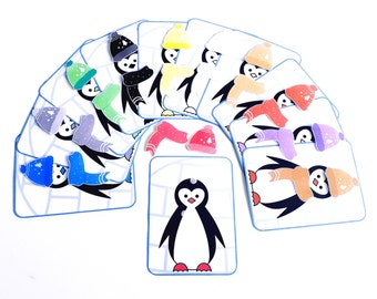 以下が含まれることがあります： 異なる色の帽子とマフラーをつけたペンギンのカードのセット。カードはマッチングゲームやアクティビティのために設計されています。