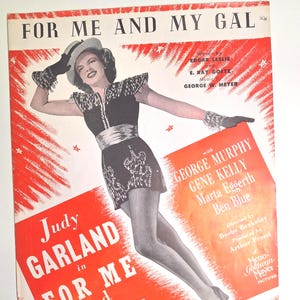 May include: Vintage sheet music cover for "For Me and My Gal" featuring Judy Garland. The cover is predominantly red and white, with a black and white image of Garland in a performance outfit. Text includes the title, cast, and production details.