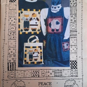 May include: A vintage sewing pattern featuring appliqued designs. The pattern includes instructions for a sweatshirt, jumper, and tote bag. The designs include a boy and girl, and a sheep. The text reads "RAGGEDY ANNA AND ANDREW BUTTON ONTM PATTERN" and "PEACE CREEK COLLECTIONS".