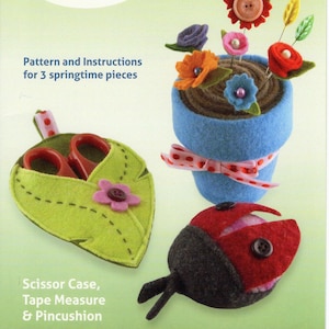 May include: A springtime sewing set featuring a felt scissor case, tape measure, and pincushion. The set includes a blue felt flower pot with felt flowers and a ladybug pincushion. The text reads "Springtime Sewing Set".