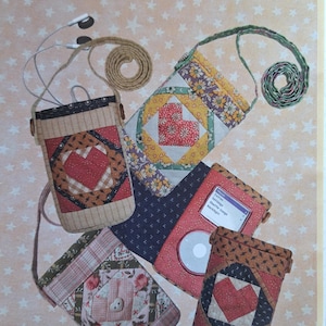 May include: Image of several handmade pod cases in various quilted patterns, including hearts and floral designs. The cases are in shades of red, brown, and blue, with the text "POD CASE" at the top. The cases are designed by Darlene Jewell-Walhood.