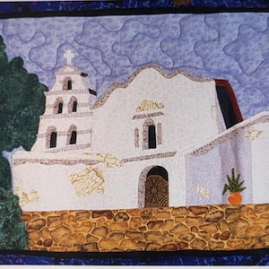 May include: A white building with a cross on top, surrounded by a stone wall and green bushes. The building has a bell tower and a large arched doorway. The sky is blue with white clouds.