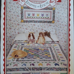 May include: A quilt pattern titled "Four Corners Beginner and Beyond" with the text "Pretty Posies All in a Row." The image shows a finished quilt on a bed, along with two dolls and a straw hat. The quilt features a colorful patchwork design.