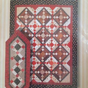 May include: A quilt pattern with a diamond design in red, brown, and cream. The pattern includes throw and queen sizes, plus a quick runner. The image also displays the "Perkins Dry Goods" logo.