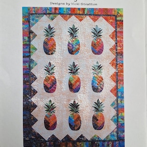 Puede incluir: Un patrón de edredón colorido con nueve diseños de piñas. Cada piña tiene un diseño de patchwork en tonos naranja, azul, verde y morado. El edredón está enmarcado con un borde estampado e incluye el texto "Sunshine Pineapple".