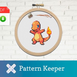 Puede incluir: Un patrón de punto de cruz de un personaje Pokemon rojo y naranja, Charmander, en un aro de bordado de madera. El patrón está disponible para descargar en PDF. La imagen incluye el texto "Pattern Keeper".