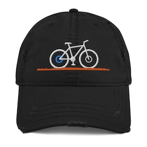 May include: A black distressed baseball cap with a white embroidered bicycle design. The bicycle has a blue tire.
