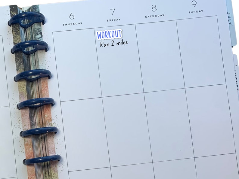 May include: A white planner with a blue sticky note that says "WORKOUT" and "Ran 2 miles" on a page labelled "Friday" in a weekly calendar.