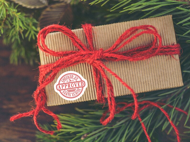 May include: A brown cardboard gift box tied with red twine and a red "Checked 2X Approved Santa Clause" sticker.