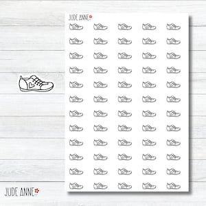 May include: A sheet of white paper with 64 black and white outline drawings of sneakers. The sneakers have a heart shape on the side. The text "JUDE ANNE" is at the top and bottom of the sheet.