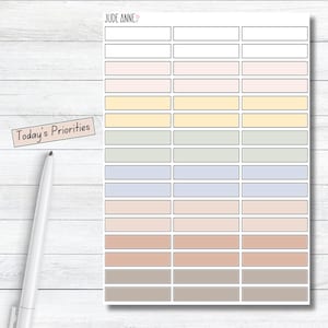 May include: A sticker sheet with the text JUDE ANNE at the top and a separate label reading Today's Priorities. The sheet contains thirty-three rectangular stickers arranged in three columns, featuring a gradient of pastel colors.