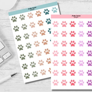 May include: Two sheets of paw print stickers. The first sheet has green, brown, and beige paw prints. The second sheet has pink, red, purple, and lavender paw prints. The sheets are labeled "Jude Anne Designs".