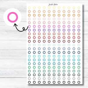 May include: A sheet of colorful circle stickers with a rainbow gradient. The stickers are arranged in rows and columns, with each row featuring a different color. The colors include yellow, orange, red, pink, purple, blue, green, and black.