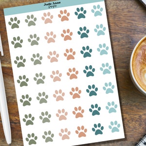 May include: A sheet of paw print stickers in various shades of green, blue, and pink. The stickers are arranged in rows and columns on a white background.
